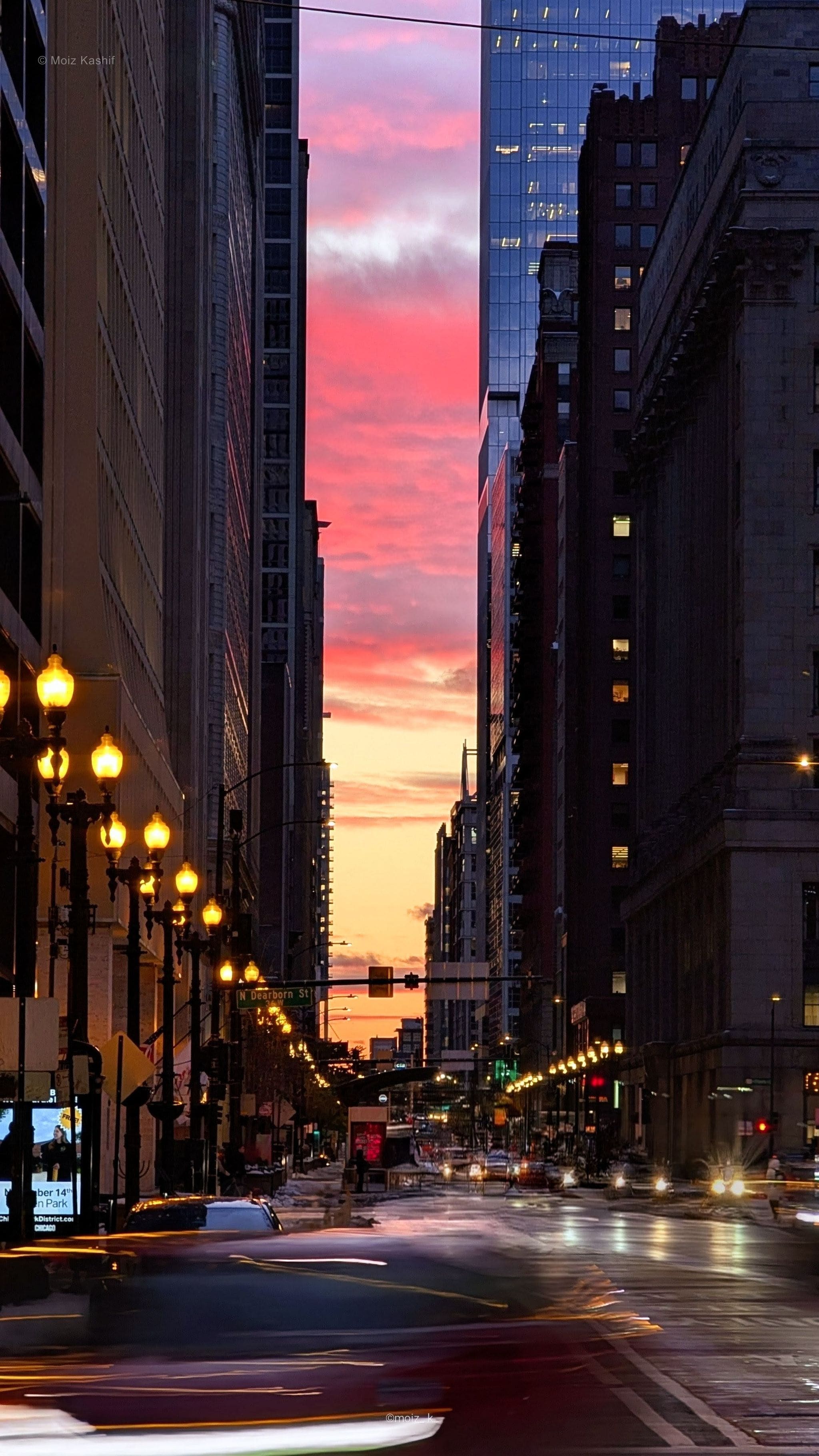 Traffic moving through downtown Chicago beneath a vivid red sunset.