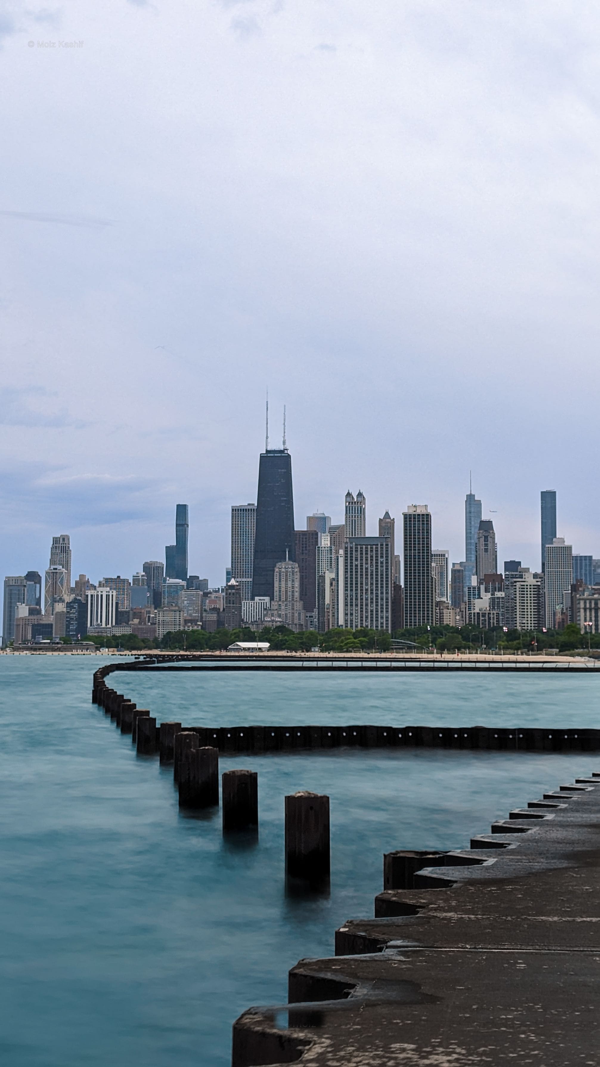 The Chicago skyline across pale water and a geometric concrete shoreline.