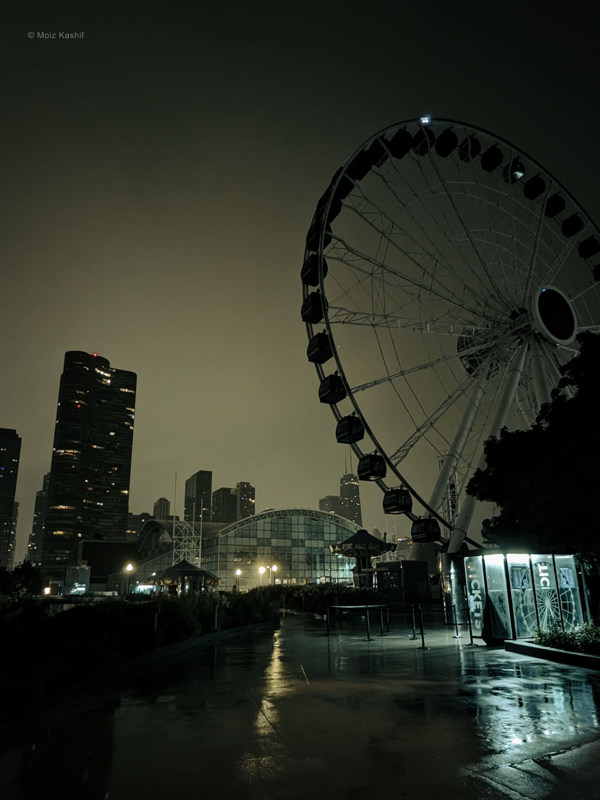 The Navy Pier Ferris wheel above an empty rain-darkened walkway.