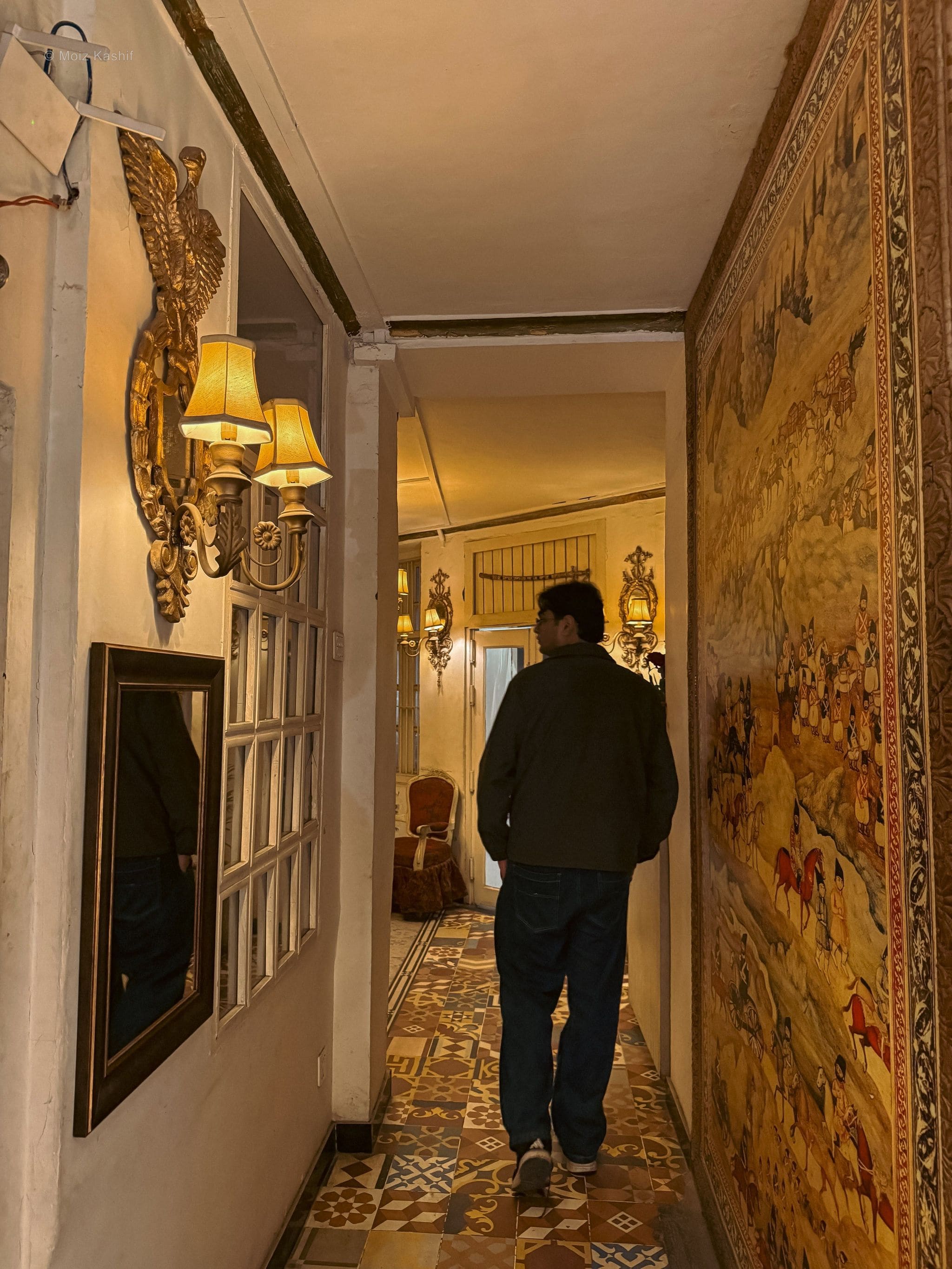 A person walking down a richly decorated interior hallway.