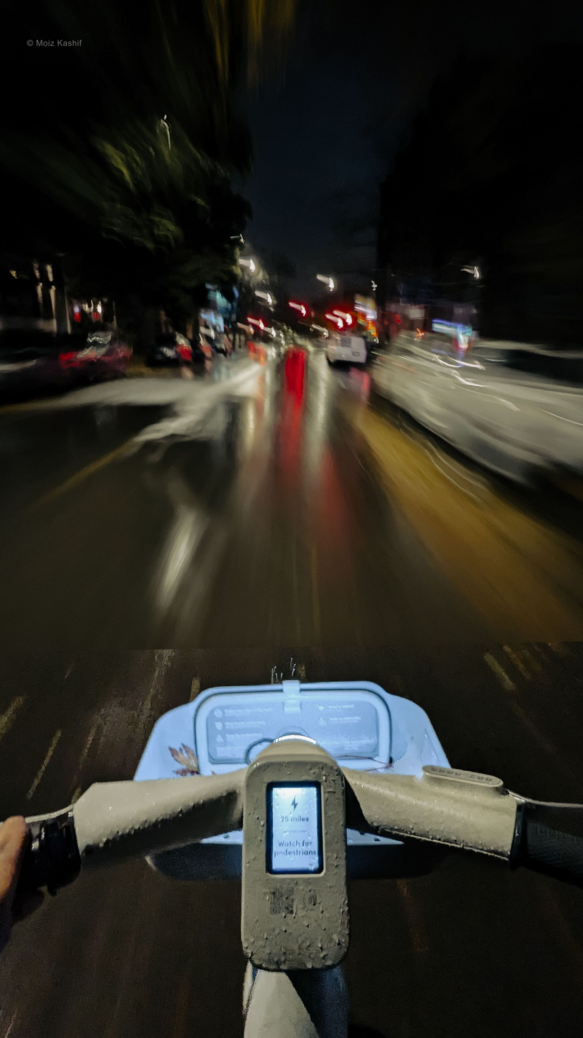 A moving bicycle seen from the rider’s perspective on a wet night.