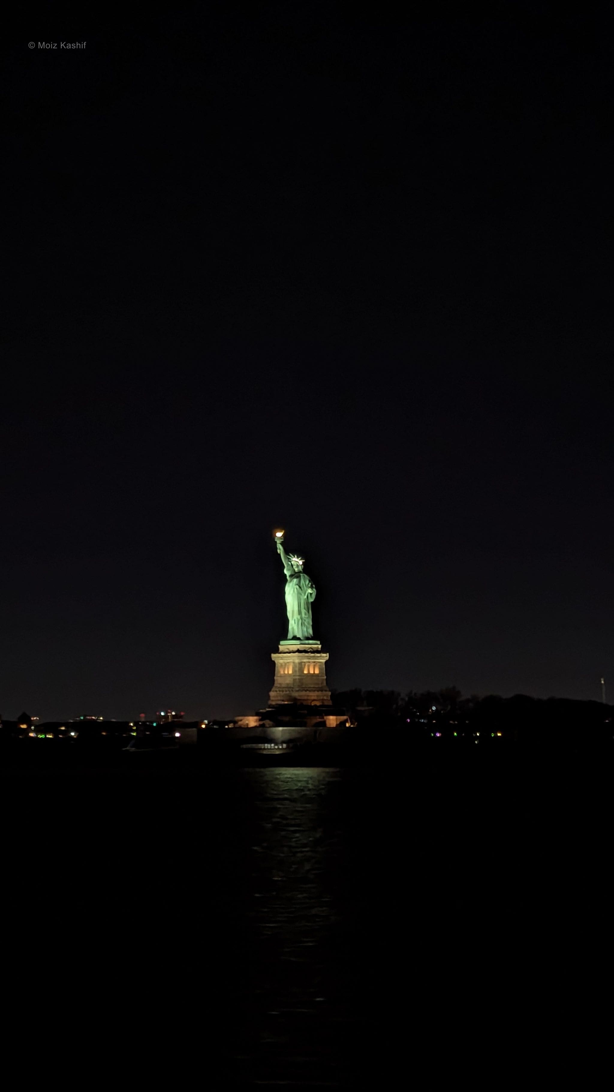 The Statue of Liberty isolated against black sky and water.