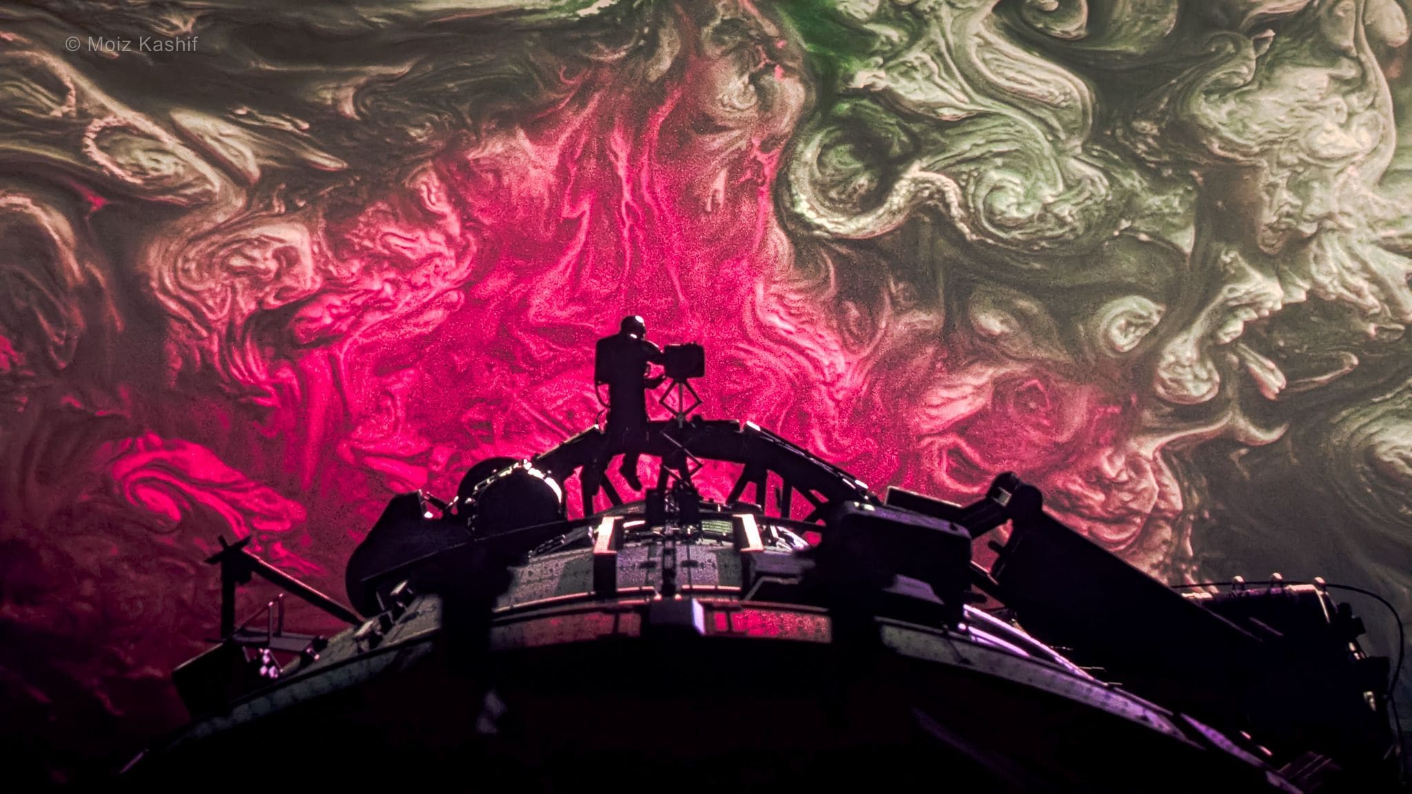 A vivid magenta liquid projection spreading across a dark ceiling.
