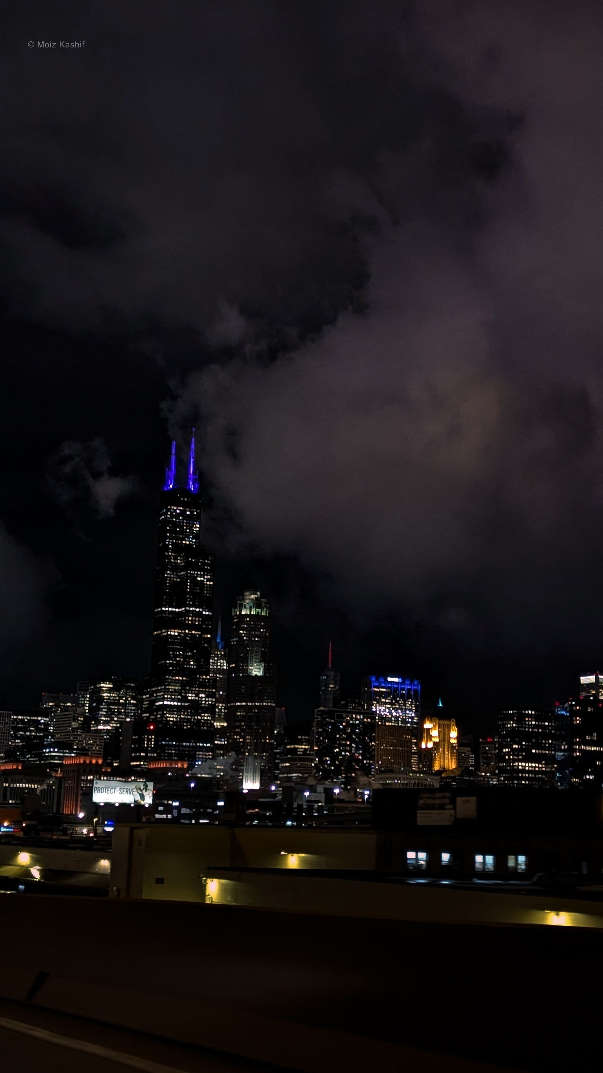 The Chicago skyline at night beneath a bank of low storm clouds.
