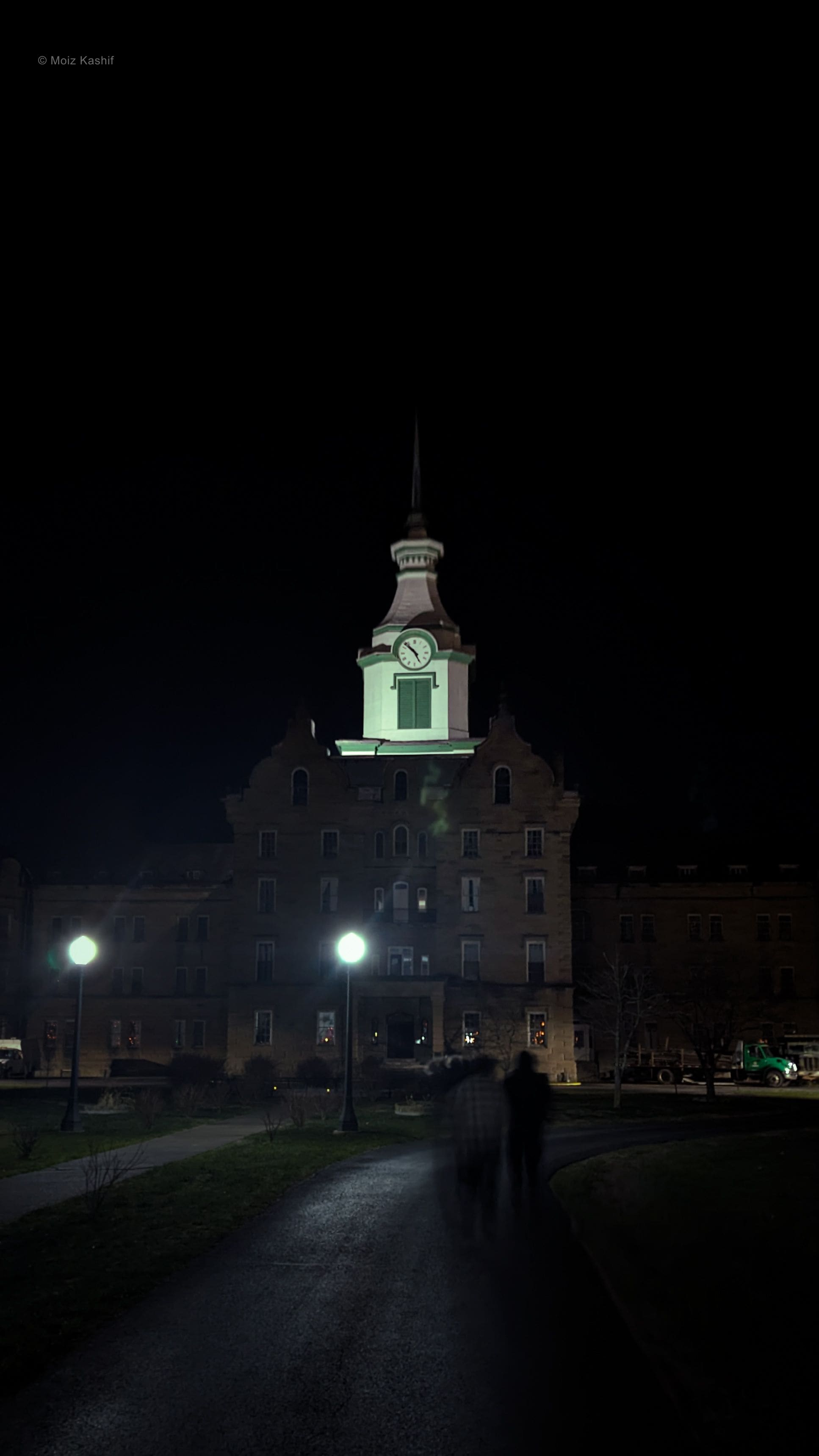 A historic campus building glowing alone beneath the night sky.